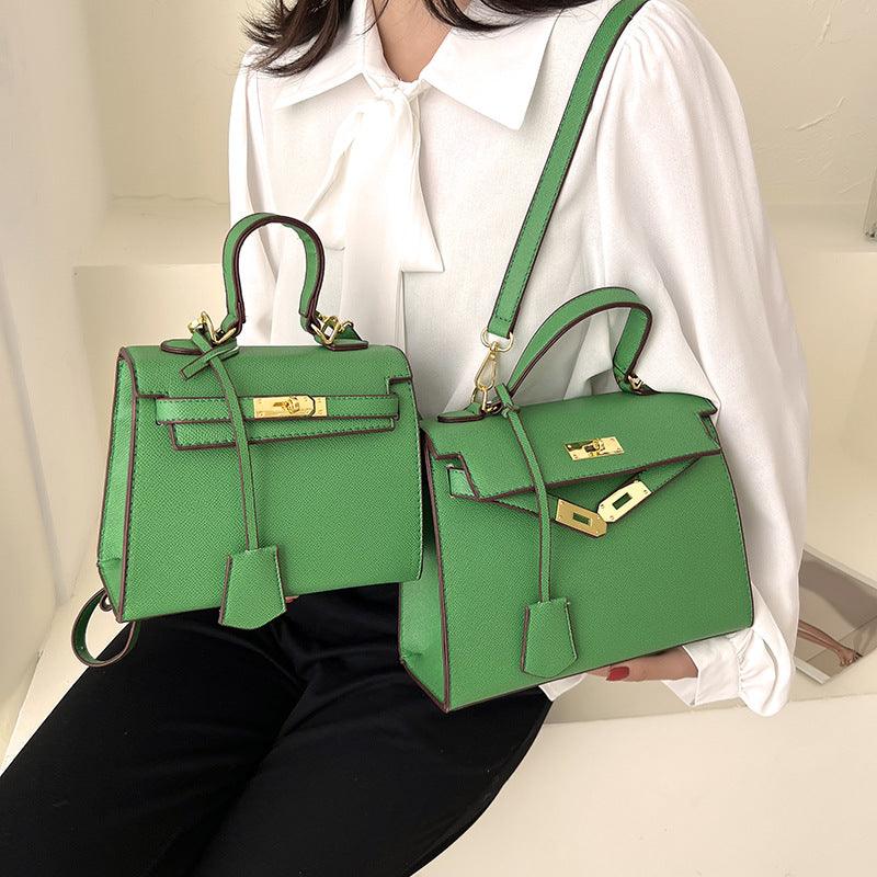 Green handbags held by a person wearing a white shirt.