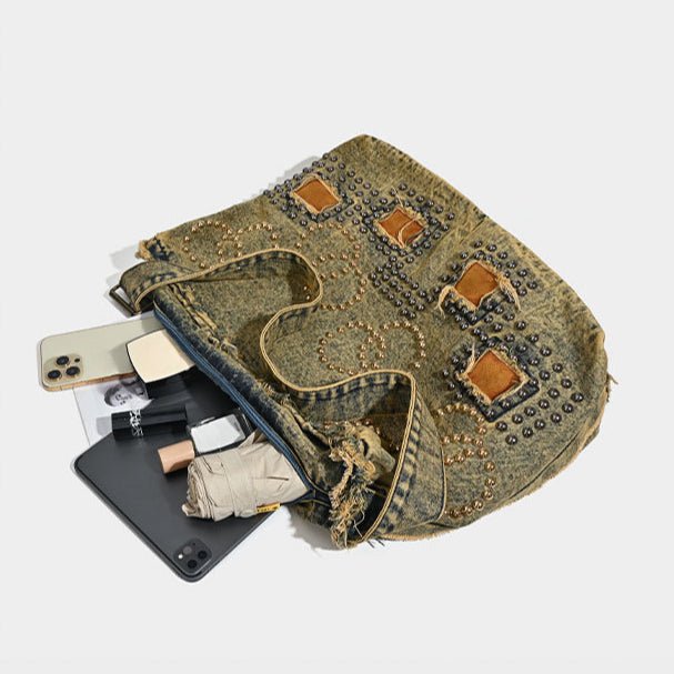 Denim pouch with studded details containing phone, cards, and other items on a white background