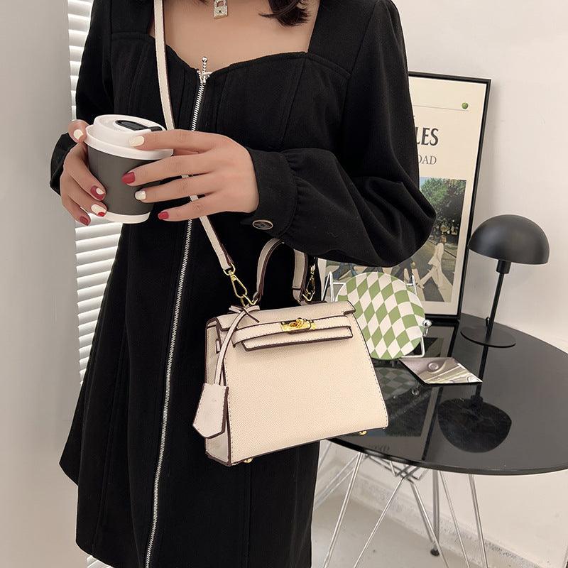 Person holding a beige handbag and a coffee cup in an indoor setting.