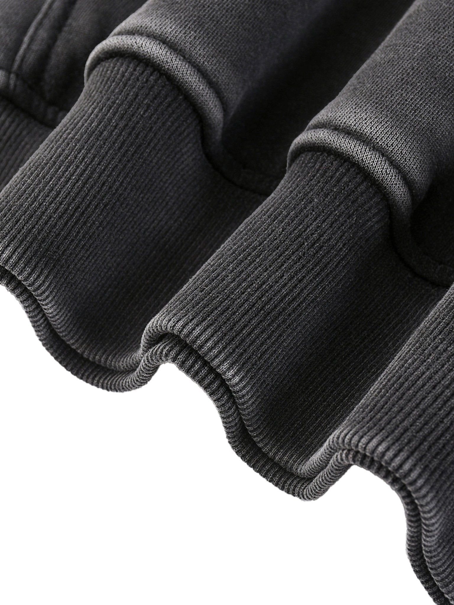 Close-up of a dark gray sweater with ribbed cuffs and hem on a white background