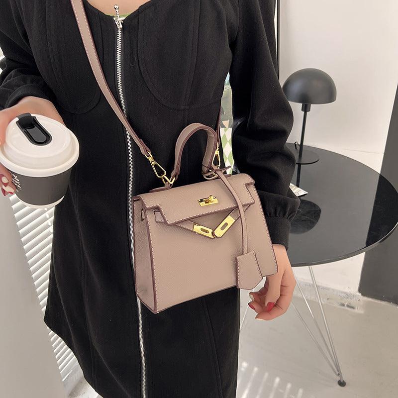 Person holding a beige handbag and a coffee cup indoors.