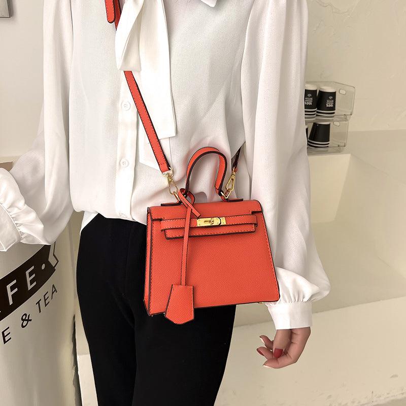 Person wearing a white shirt and black pants with an orange handbag.