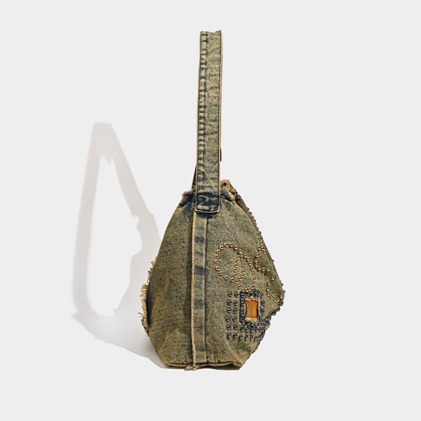 Denim sling bag with decorative elements on a white background