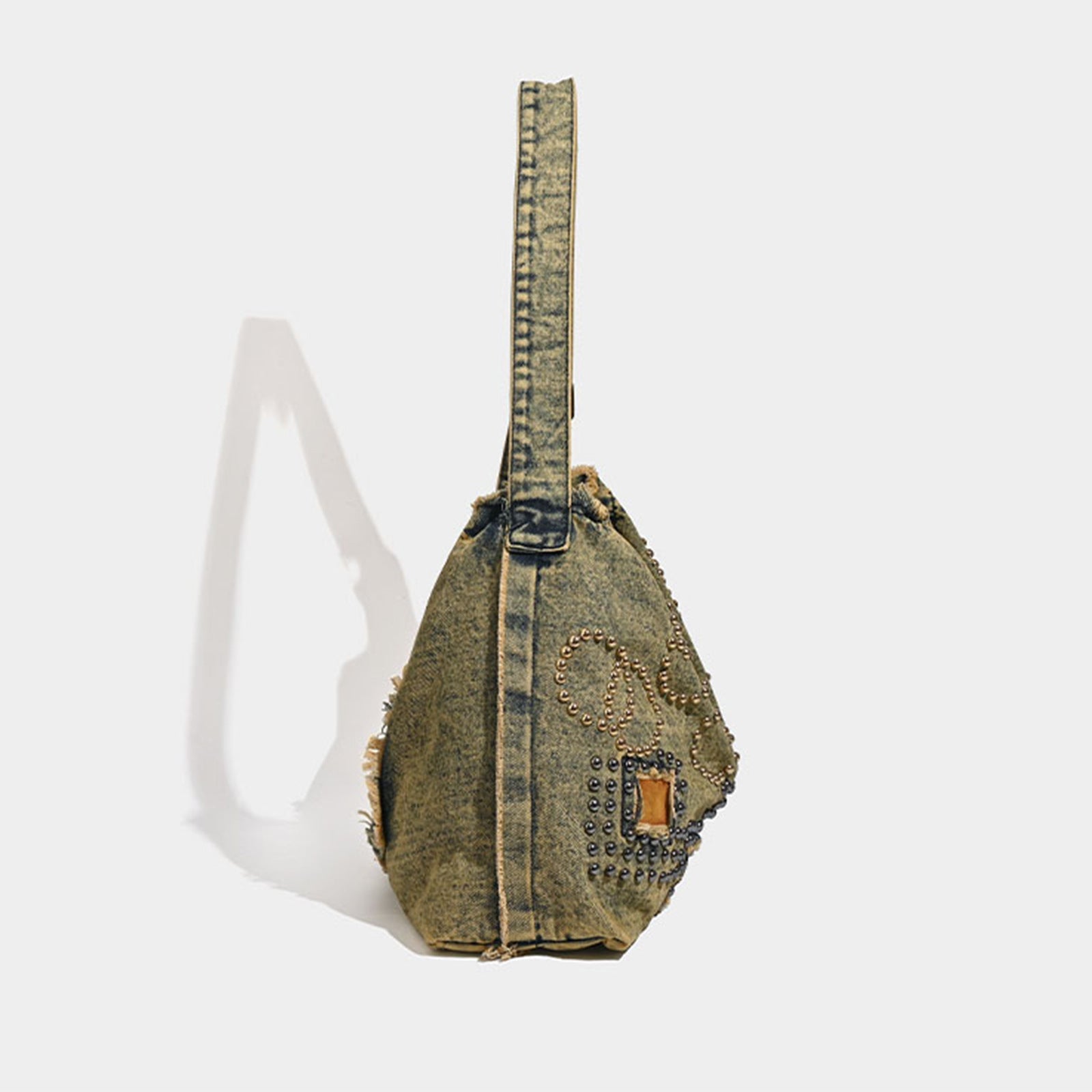 Denim sling bag with decorative elements on a white background
