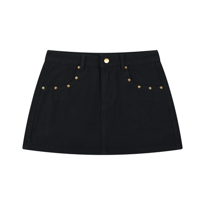 A black denim mini skirt with gold-tone metal studs and a button closure, displayed flat against a solid white background.