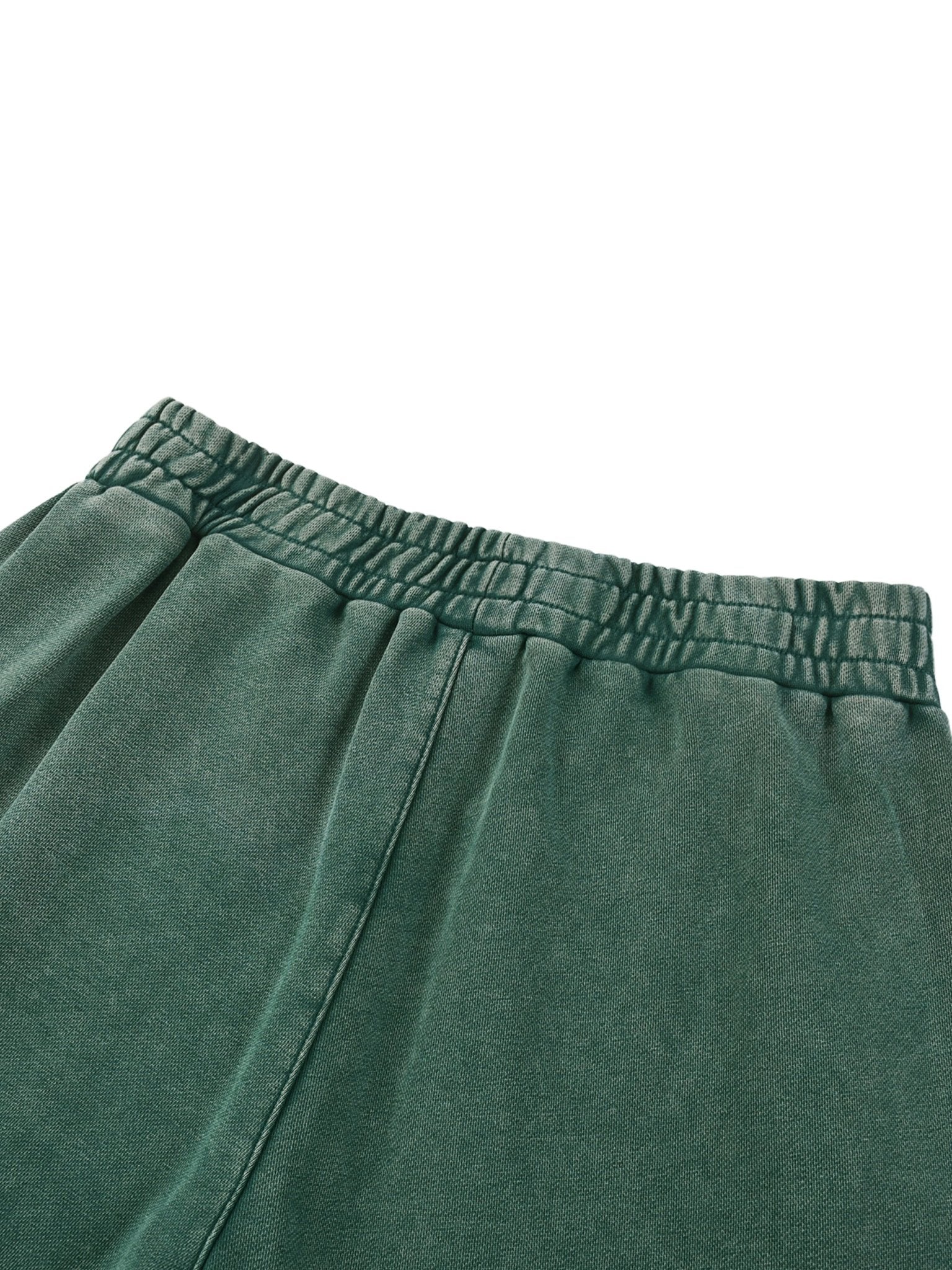 Close-up of green sweatpants with an elastic waistband on a white background