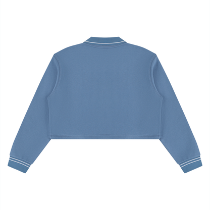 A cropped long-sleeve sweatshirt in dusty blue, shown from the back with white contrast stitching on the collar and cuffs, set against a plain white background.