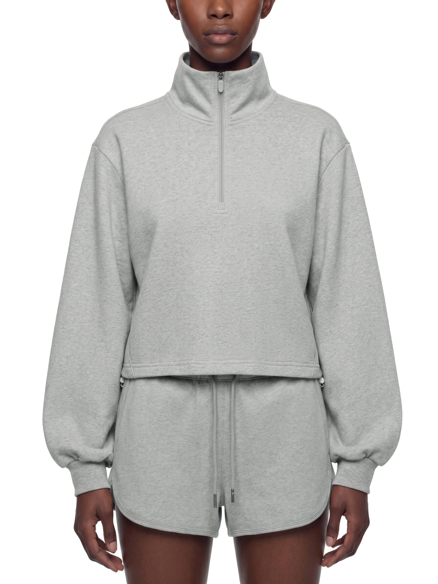 Person wearing a gray quarter zip crop sweatshirt on a white background