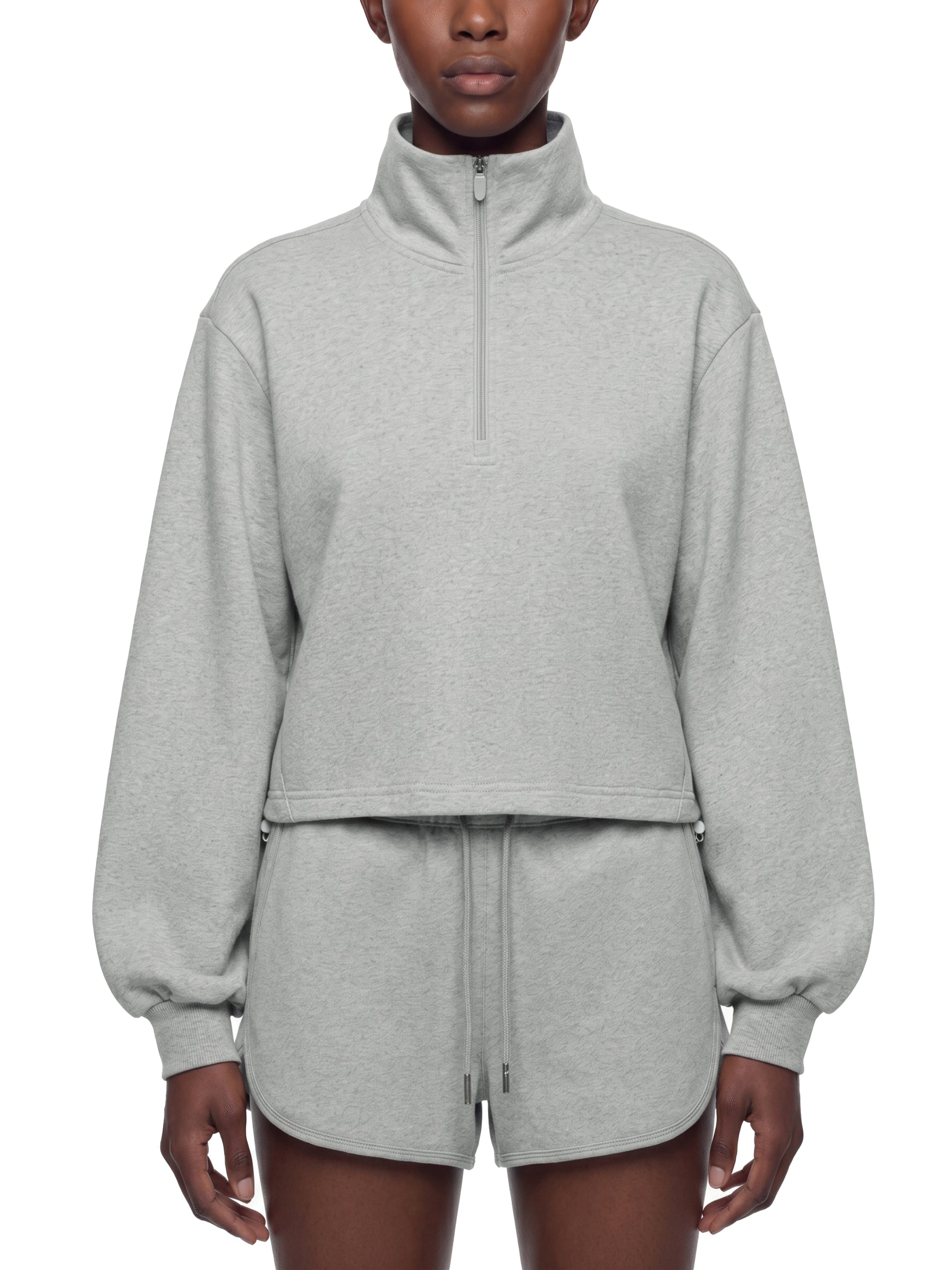 Person wearing a gray quarter zip crop sweatshirt on a white background