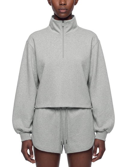 Person wearing a gray quarter zip crop sweatshirt on a white background