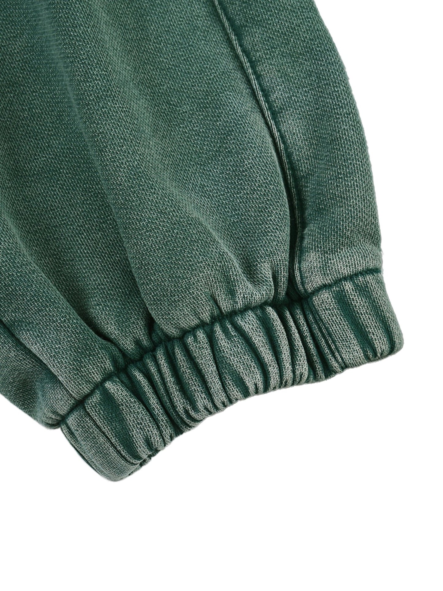 Close-up of Green sweatpant fabric showing its textured pattern on a white background